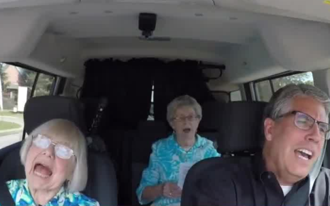 Two seniors and middle aged man singing in a car